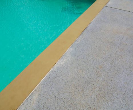 Cement or concrete gravel floor beside of swimming pool .